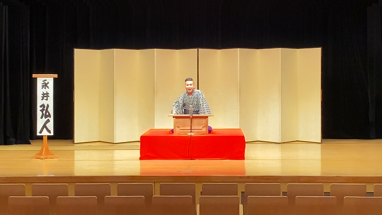 金屏風の前で高座に上がり、講談の演目「菜豆腐（徂徠豆腐）」を披露するアトオシ 永井弘人。